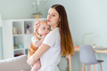 Photo of charming shiny lady wear white t-shirt smiling holding arms hands baby singing song inside...