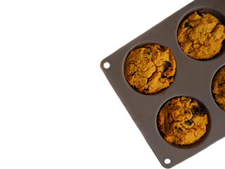 four gluten- and lactose-free pumpkin cupcakes, sprinkled with pumpkin seeds, lie in a gray silicone mold. top view. vegan sweets