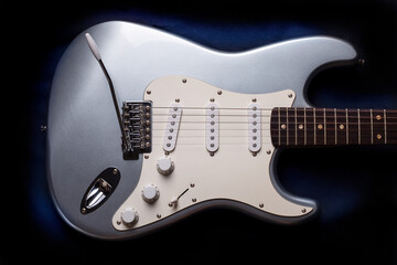 Silver electric guitar isolated on black background.