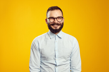 Portrait of happy young handsome guy looking at camera, glad to find suitable well paid job, isolated over yellow background