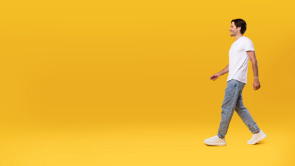 Fototapeta na wymiar Young bearded man walking isolated on yellow background, panorama