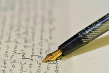 Fountain pen on a blurred letter background. Old fountain pen on an vintage handwritten letter....