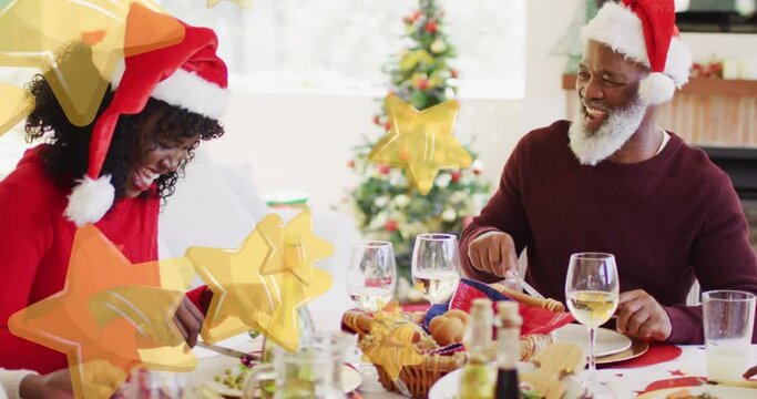 Yellow star falling against african american family laughing while having dinner during christmas