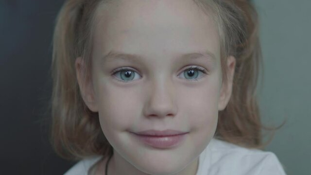 Cute little girl kid looking at camera. Portrait of young female child with big blue eyes. Concept of children and kids 