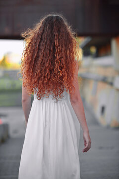 back view of woman with long curly hair and white dress