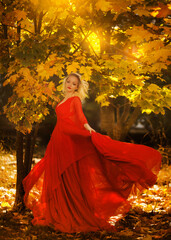 beautiful young girl with white hair in a red dress dancing in the autumn forest