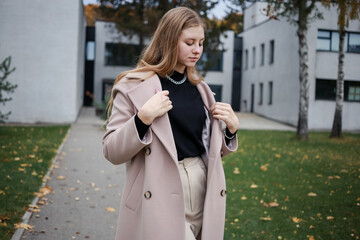 Fototapeta premium The girl on the street straightens her coat