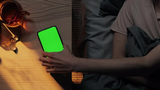 Woman resting in bed and using mobile with green screen