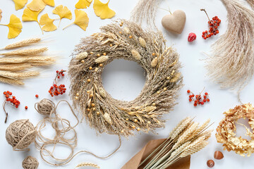 Dried pampas boho grass wreath. Off white table with ginko leaves, stones, rowan berries, grass and...