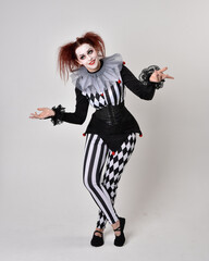   halloween, character, costume, figure pose, posing, portrait, gesture,  isolated,  magical, dynamic movement,  isolated,  studio background,  red hair, circus, theatre, jester, clown,  
full length,