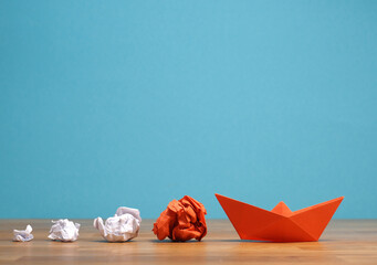 Teamwork business concept with crumpled paper and a paper boat on a wooden office table