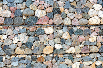Stone wall with metal grid and rough stones as background