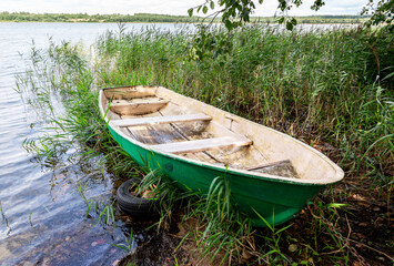 Old plastic fishing boat on the bank of the lake