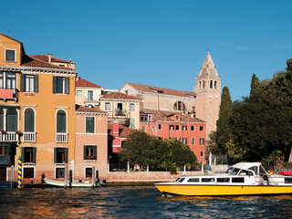 Grand Canal in Venice, Italy. Passenger vaporetto boat and historic buildings with church bell tower, belfry. Venetian passenger water transport, logos removed for commercial use. - obrazy, fototapety, plakaty