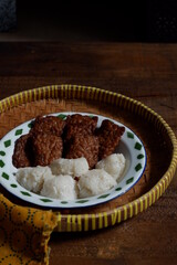a plate of tempeh cooked in brown spice served with glutinous rice balls