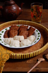 a plate of tempeh cooked in brown spice served with glutinous rice balls