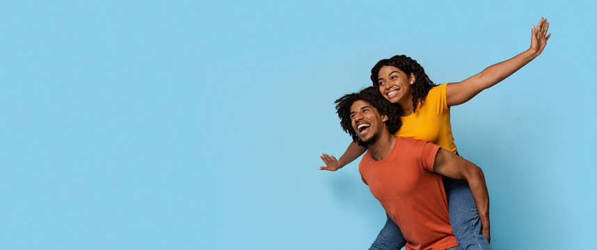 Happy black lovers making airplane and looking at copy space