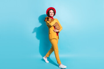 Full length body size view of attractive cheerful girl going carrying doggy isolated over bright blue color background