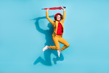 Full length body size view of attractive cheerful girl jumping holding umbrella isolated over bright blue color background