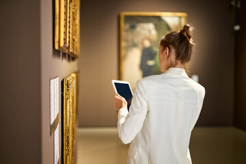Woman visitor in the historical museum looking at pictures - obrazy, fototapety, plakaty
