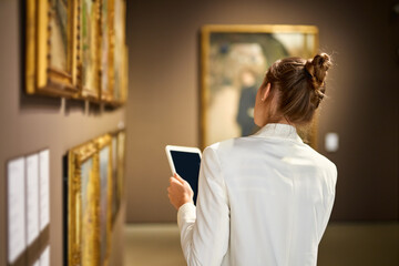 Fototapeta na wymiar Girl Museum Paintings Exhibition Looks Tablet.