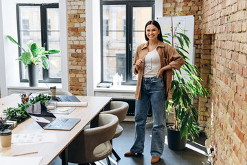 Portrait of young caucasian woman looking at the camera and smiling in a loft modern workplace. Business lady with glasses