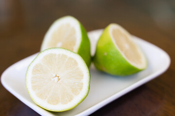 Fototapeta na wymiar Closeup on lime halves on small plate. Green lemon slices