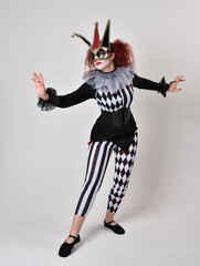 Obraz premium halloween, character, costume, figure pose, posing, portrait, gesture, isolated, magical, dynamic movement, isolated, studio background, red hair, circus, theatre, jester, clown, full length,