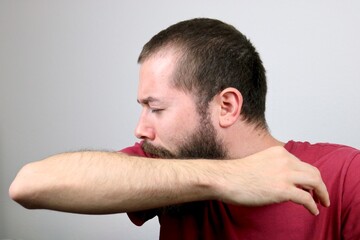 Fototapeta premium Sick caucasian man sneezing into elbow