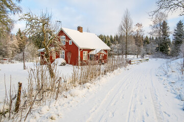 Red house at the roadside in snowy winter landscape - obrazy, fototapety, plakaty