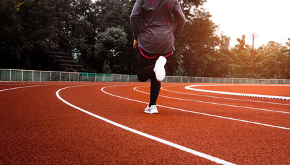 Athletic woman in sport clothes running on stadium track. Female runner jogging for exercise....