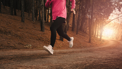 Athletic woman running on forest trail. Female runners running in nature in the morning. Workout...