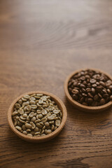 Green coffee beans next to roasted coffee beans on a stand on a wooden table. Unroasted coffee. Roasted coffee. Raw coffee.
