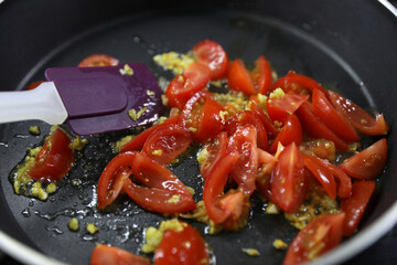 Making a sauce with olive oil, garlic and tomatoes