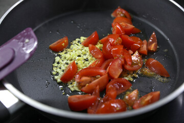 Making a sauce with olive oil, garlic and tomatoes