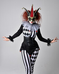 close up portrait of red haired  girl wearing a black and white clown jester costume, theatrical...