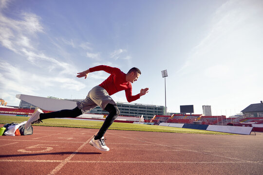 A young man is practicing a low start at an athletic training at the stadium. Sport, athletics, athletes
