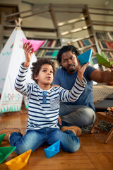 Father and son enjoying playing with paper boats at home together. Family, together, love, playtime