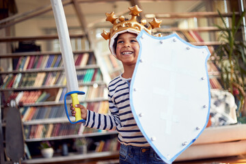 A cheerful little boy dressed as knight is posing for a photo while enjoying a playtime at home....