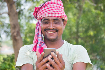 farmer of Indian ethnicity holding mobile in the nature outdoor