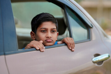 Cute Indian Child waving from car window.