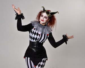 close up portrait of red haired  girl wearing a black and white clown jester costume, theatrical...