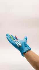 The doctor's hand in a blue glove holds 3 syringes with a blue, yellow and scarlet vaccine. Covid-19 vaccination