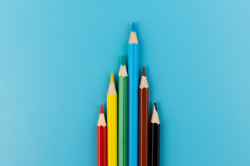 Six colored pencils close-up on a blue background with a copy of the space. The texture of bright colored wooden pencils.