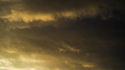 Reflets jaunâtres sous un cumulonimbus illuminé par le soleil couchant, dont les rayons s'infiltrent par sa base.  Cet orage est en phase de dissipation