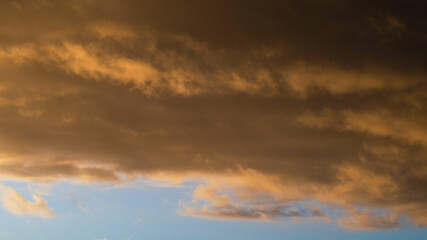 Reflets jaunâtres sous un cumulonimbus illuminé par le soleil couchant, dont les rayons s'infiltrent par sa base.  Cet orage est en phase de dissipation