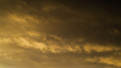 Reflets jaunâtres sous un cumulonimbus illuminé par le soleil couchant, dont les rayons s'infiltrent par sa base.  Cet orage est en phase de dissipation