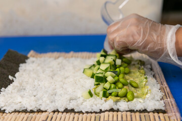 Manos preparando un rollo de Uramaki 
