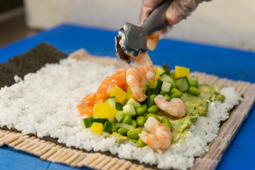 Manos preparando un rollo de Uramaki 