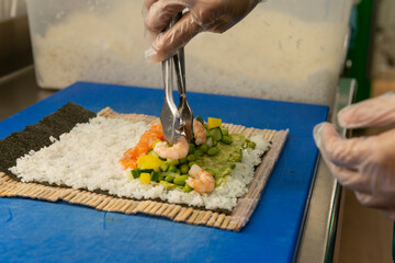 Manos preparando un rollo de Uramaki 